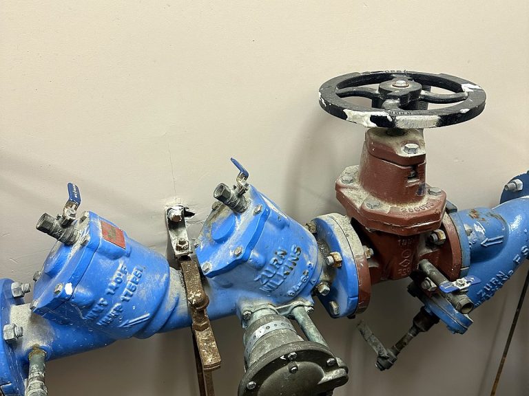Blue backflow preventer assembly with copper piping on a wall