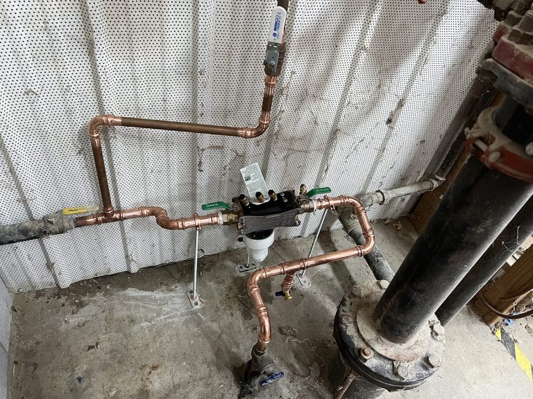 Copper piping and a backflow assembly on a block wall