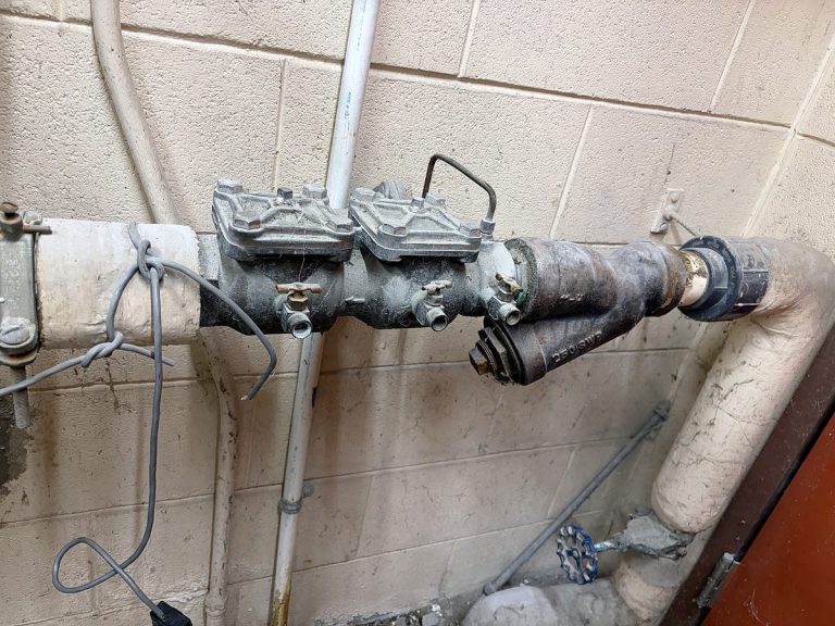 Backflow preventer mounted on a painted block wall