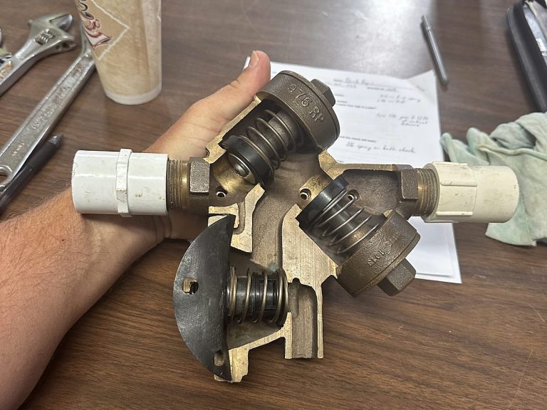 Cutaway backflow preventer and a wrench on a workbench