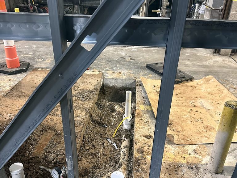 PVC drain stubs set in gravel inside a commercial building frame