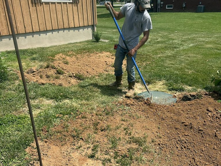Plumber raking soil in a yard after a repair