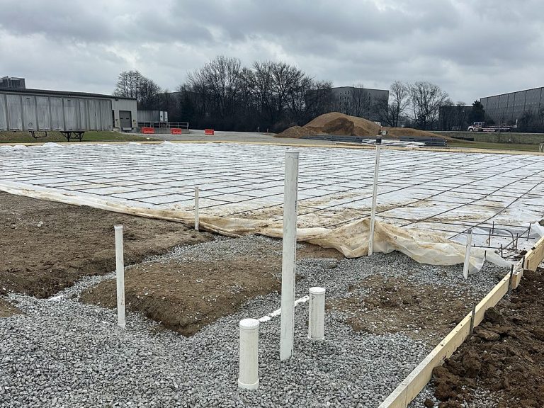 Plumbing stub-outs and gravel across a slab before concrete