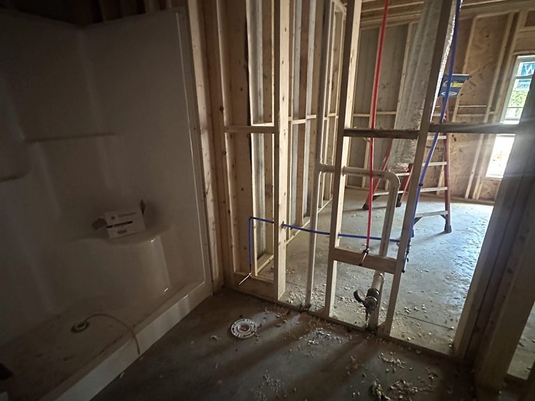 Red PEX and PVC lines roughed into wall framing