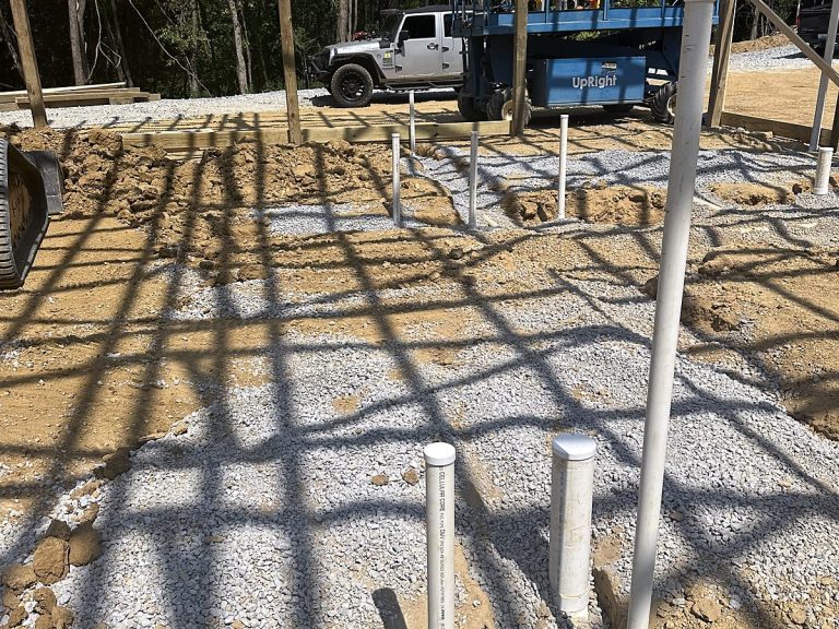 Plumbing stub-outs in gravel with construction equipment behind