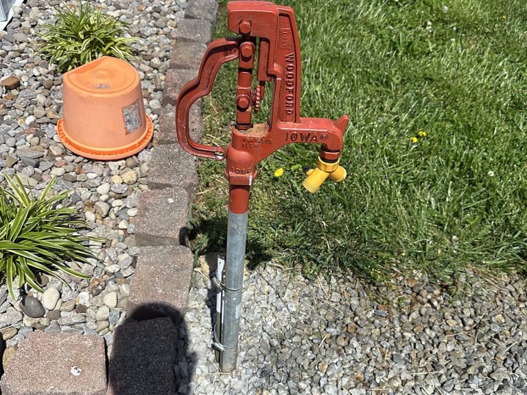 Red yard hydrant beside a house with gravel landscaping