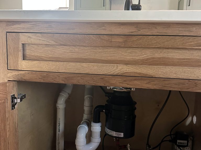 Under-sink plumbing with garbage disposal in a wood vanity