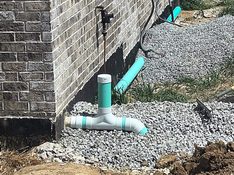 PVC sewer cleanout at a brick foundation