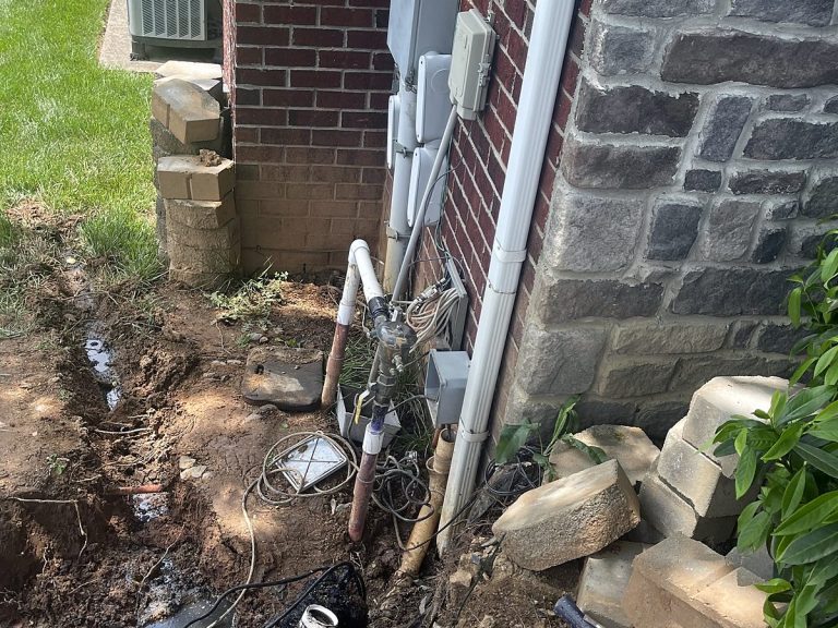 Plumbing work at the base of a stone-clad house