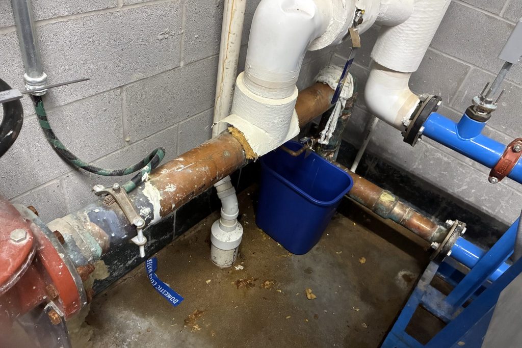 Copper pipe repair in progress on a block wall