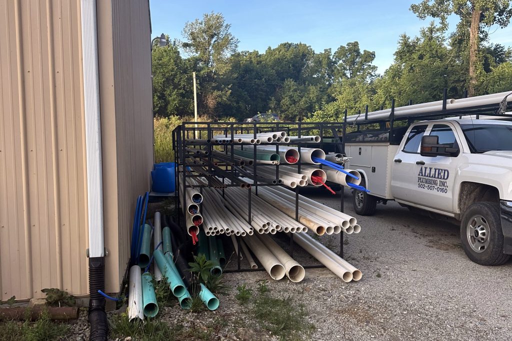 Pipe stock and service trucks outside the Allied Plumbing shop