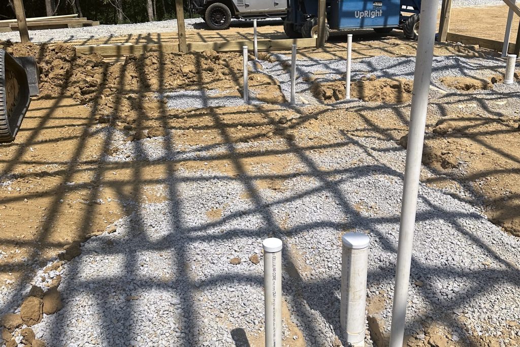 Plumbing stub-outs through the gravel pad before a slab pour