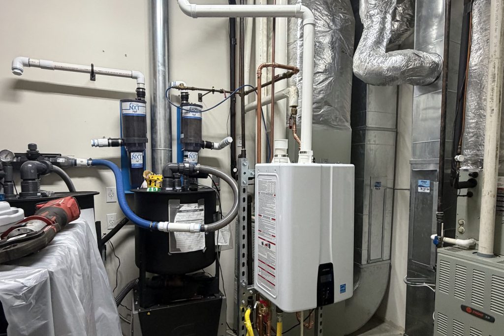 Tankless water heater beside a furnace on a job site